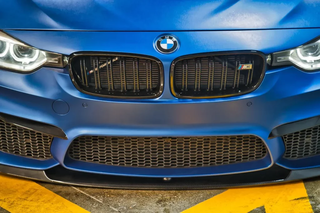 BMW Frontansicht mit typischer Doppelniere, blauer Lackierung und defektem Motor oder Getriebe